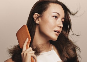 Woman brushing her hair with Aveda's wooden paddle brush